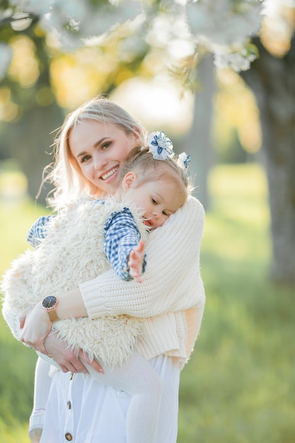 Uma linda jovem mãe com sua filha estão descansando em um piquenique no jardim florido