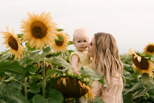 Uma linda jovem mãe com sua filha fofa em um campo de girassóis