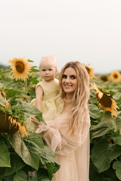 Uma linda jovem mãe com sua filha fofa em um campo de girassóis