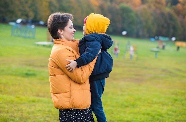 Uma linda jovem mãe segura seu filho pequeno em seus braços, mãe e filho passam tempo juntos no