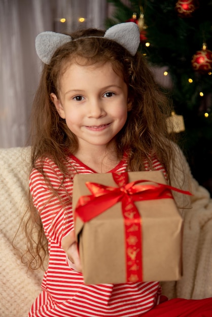 Uma linda jovem senta-se no sofá com o presente Natal Ano Novo