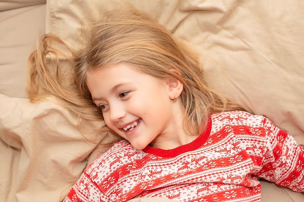 uma linda loira de pijama de ano novo está deitada em uma cama com roupa de cama de linho