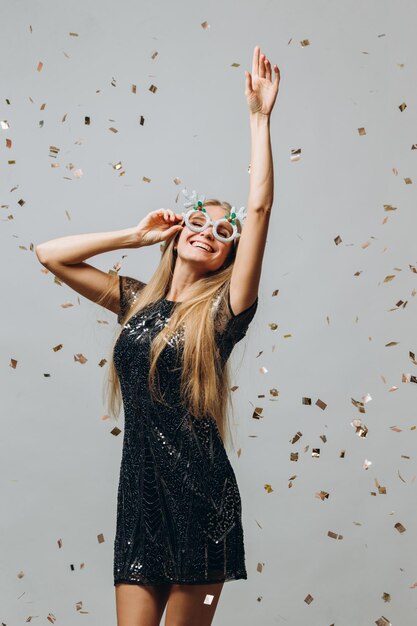 Foto uma linda loira está dançando sob o conceito de festa de ano novo de confete brilhante