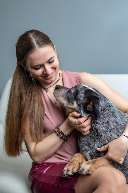 uma linda loira está sentada no sofá e abraçando um cão curandeiro