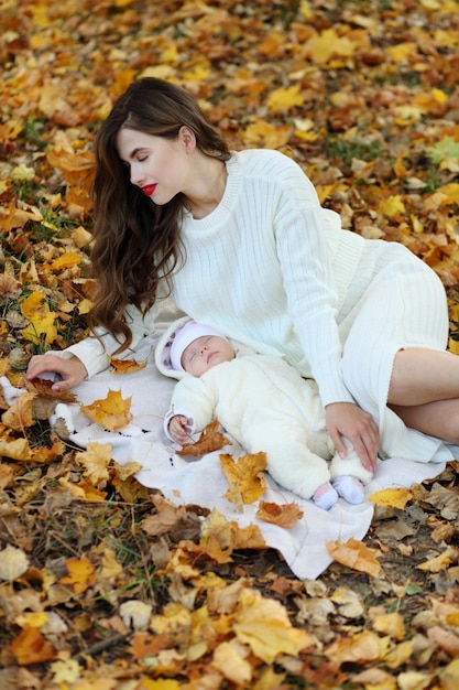 Uma linda mãe e suas filhas estão andando no parque outono