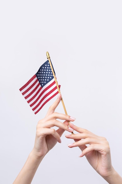 Uma linda mão feminina segura uma bandeira americana em um fundo branco