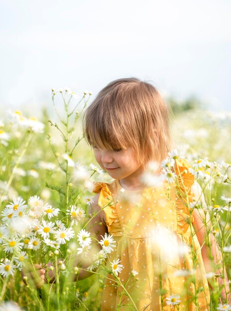 Foto uma linda menina a cheirar margaridas no campo.