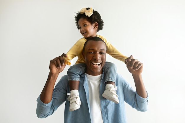 Foto uma linda menina afro-americana sentada no pescoço do pai.