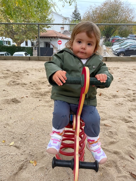 Foto uma linda menina brinca em um cavalo de madeira em um parque em um dia nublado