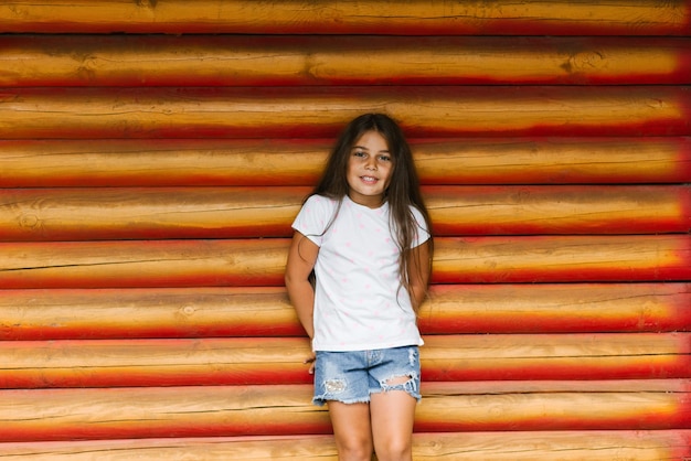 Uma linda menina posando no fundo de uma parede de madeira