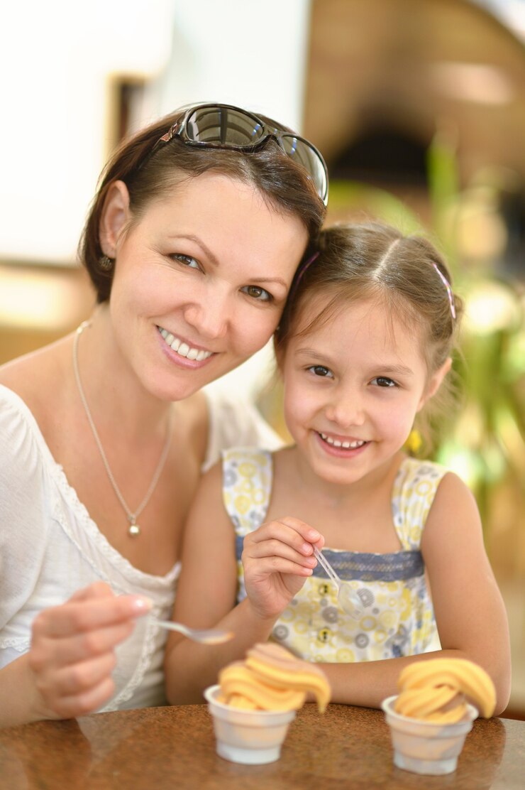 Foto uma linda menina tomando sorvete com a mãe