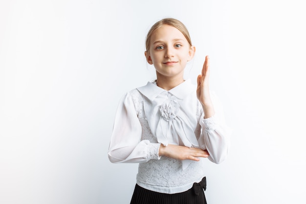 Uma linda menininha menina, puxa a mão em uma parede branca