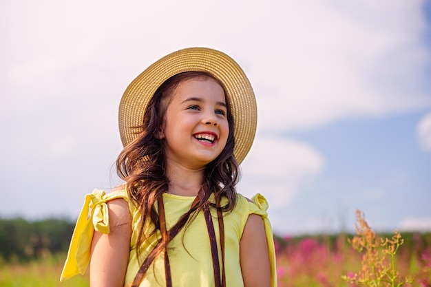 Uma linda morena feliz com um chapéu de palha fica na natureza no verão