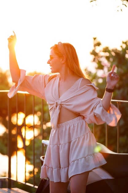 Foto uma linda mulher ao pôr do sol está em um terraço com vista para o mar. foto de alta qualidade