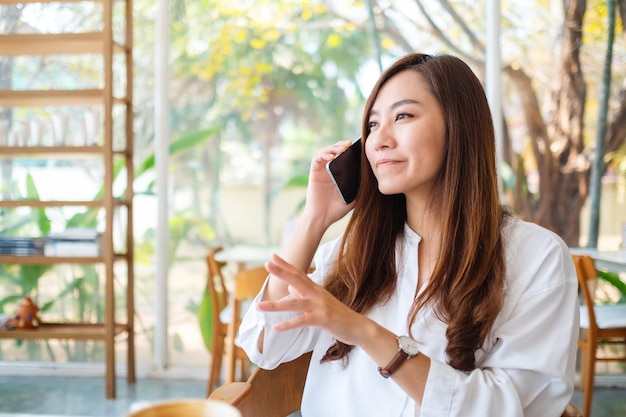 Uma linda mulher asiática falando ao celular em um café