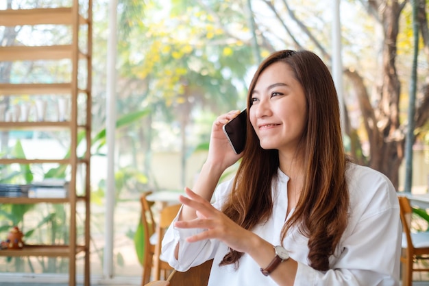 Uma linda mulher asiática falando ao celular em um café