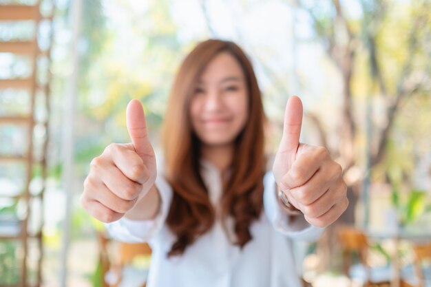 Foto uma linda mulher asiática feliz fazendo e mostrando os polegares para cima sinal com a mão