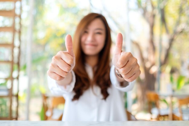 Uma linda mulher asiática feliz fazendo e mostrando os polegares para cima sinal com a mão