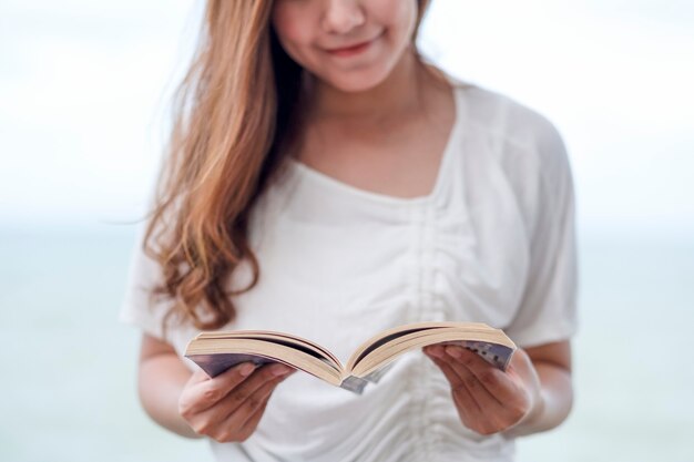 Uma linda mulher asiática lendo um livro à beira-mar