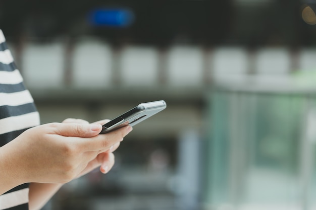 Uma linda mulher asiática usa um smartphone no centro da cidade para procurar vários