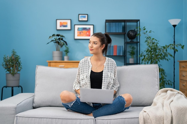 Uma linda mulher atraente apaixonada por um homem recém-conhecido senta-se no sofá com o laptop no colo