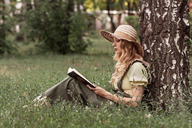 Uma linda mulher com cabelo loiro no parque ou jardim lendo um livro