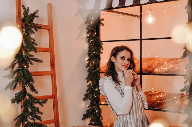 Uma linda mulher com um avental listrado sentada em um café no Natal e no Ano Novo
