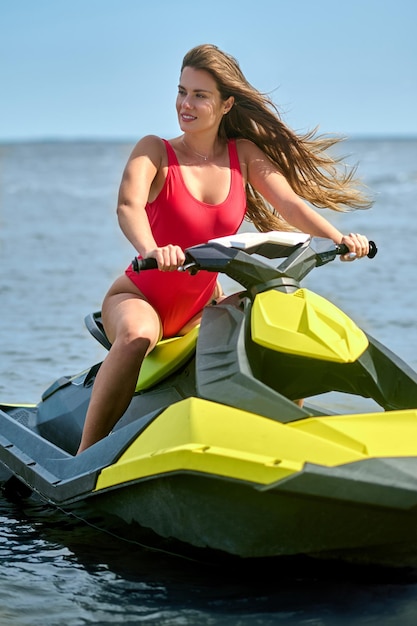 Uma linda mulher de maiô vermelho em uma scooter de água