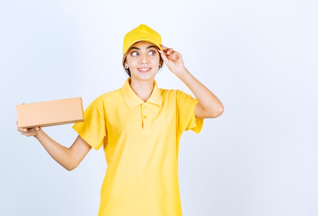 Uma linda mulher de uniforme amarelo segurando uma caixa de papel artesanal em branco.