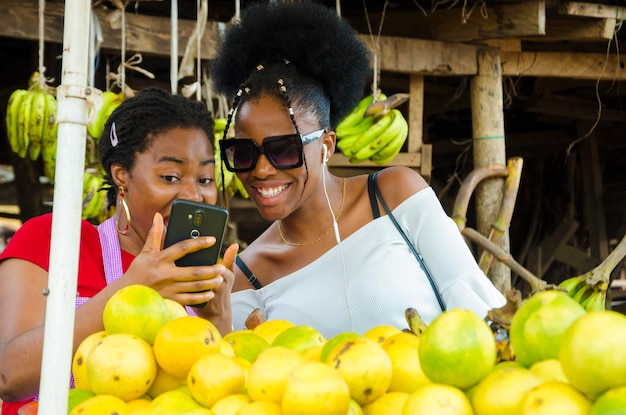 Uma linda mulher do mercado africano e seu cliente se sentindo surpresos com o que eles estão no celular