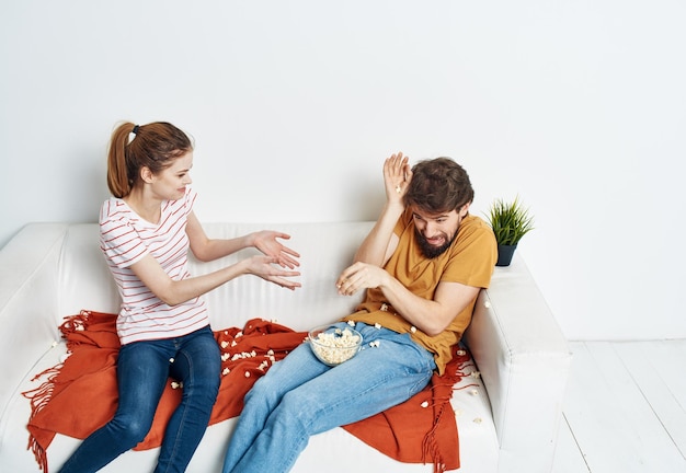 Uma linda mulher e um homem barbudo assistindo TV no sofá dentro de casa