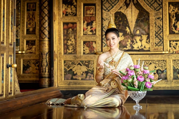 Uma linda mulher em traje nacional tailandês durante o período Ayuthaya estava sentada em uma série de guirlandas.