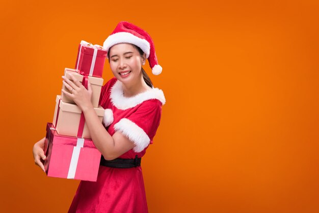 Uma linda mulher fantasiada de Papai Noel com muitas caixas de presente por ocasião do Feliz Natal e Feliz Ano Novo.