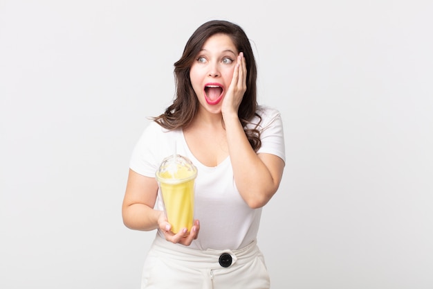 Uma linda mulher feliz, animada e surpresa segurando um milkshake de baunilha