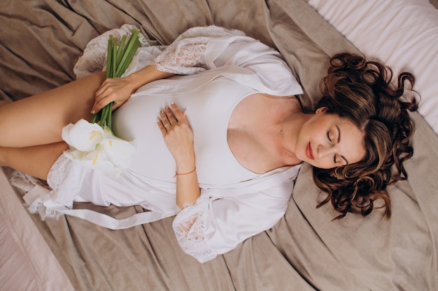 Uma linda mulher grávida deitada em uma cama em um hotel