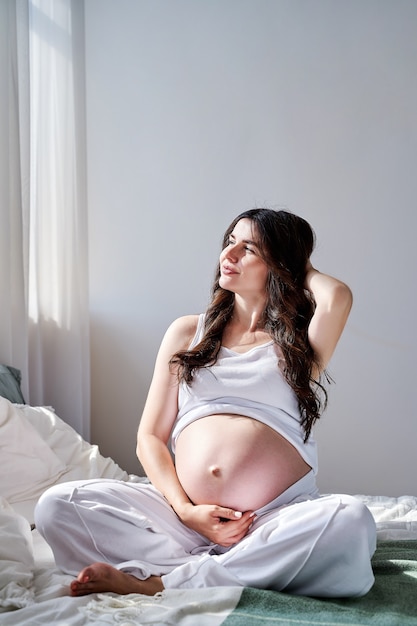 Foto uma linda mulher grávida sorri e desvia o olhar