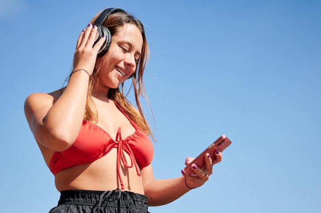 Uma linda mulher hispânica ouvindo música e usando o telefone em um dia ensolarado