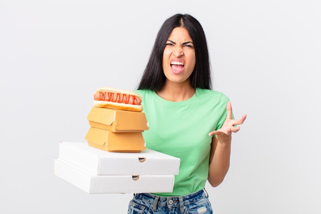 Uma linda mulher hispânica parecendo zangada, irritada e frustrada segurando caixas de fast food para levar