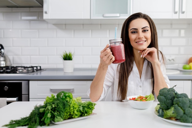 Uma linda mulher morena demonstrando um smoothie