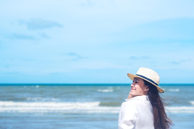 Uma linda mulher passeando na praia com o mar e o céu azul de fundo