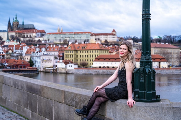 uma linda mulher posa para a câmera, em Praga, na Ponte Carlos