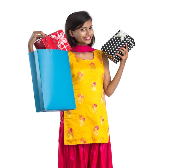 Uma linda mulher posando com uma sacola de compras e caixas de presente em um branco.