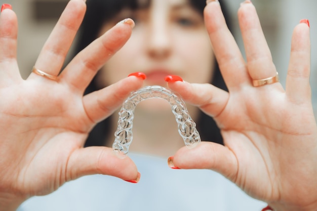 Uma linda mulher sorridente segura alinhadores invisíveis em suas mãos para alinhar os dentes para fins ortodônticos espaço para cópia