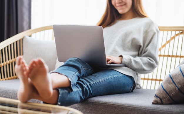 Uma linda mulher usando e trabalhando em um laptop enquanto estava deitada em um sofá em casa