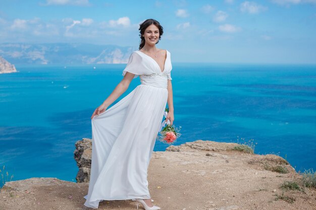 Uma linda noiva em pé na costa A noiva nas montanhas Casamento Romântica linda noiva de vestido branco posando no fundo do mar