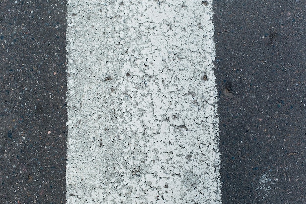 Uma linha branca na estrada com a palavra "parar" nela