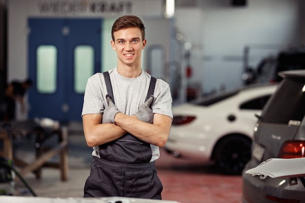 Uma loira atraente mecânica de automóveis está sorrindo durante uma pequena pausa em uma oficina mecânica.