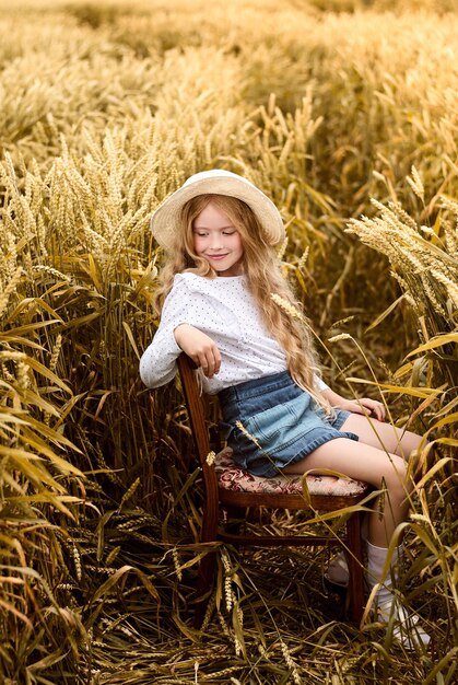 uma loira está sentada em uma cadeira em um campo. a garota de chapéu. uma garota com margaridas.