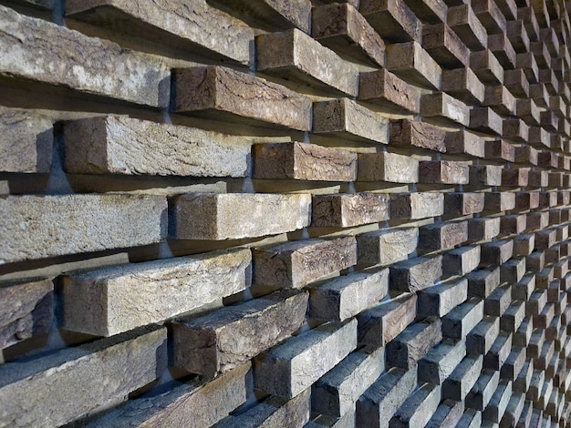 Uma longa parede de tijolos em perspectiva. Tijolos são dispostos em um padrão com diferentes profundidades de tijolo
