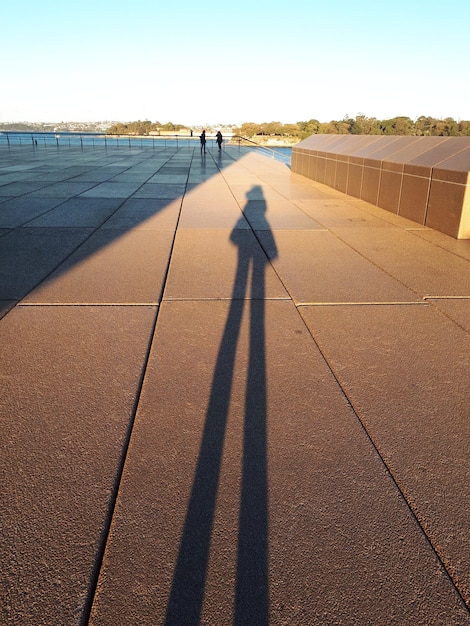 Uma longa sombra ao pôr do sol com duas figuras à frente Sydney 19 de agosto de 2019